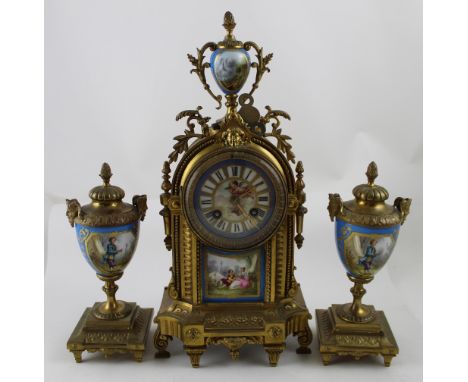 An early 20th century brass and ceramic clock garniture in the French style, gilded clock with hand painted ceramic urn to th