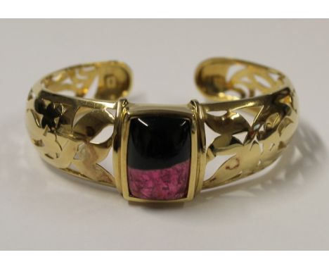 An 18ct yellow gold bangle, floral cut-outs with central rectangular cabochon amethyst stone, approx 34.8g.