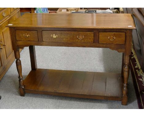 A Titchmarsh and Goodwin Style Three Drawer Oak Serving Table, with shelf stretcher, 117cm by 48cm by 80cm