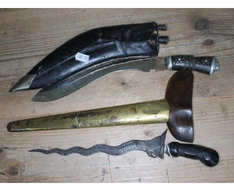An Indonesian dagger in brass and wood sheath and a late 19th century Kukri knife in leather sheath. 