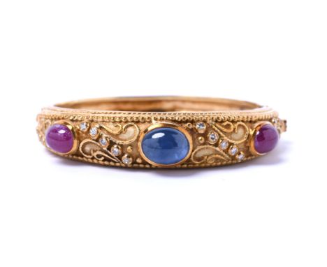 18 kt. Gouden stijve armband met krulmotieven, Centraal bezet met een cabochon geslepen Ceylon saffier van ca. 6.74 ct. met a