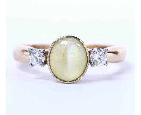 14 kt. Gouden driesteens ring, bezet met een chrysoberyl kattenoog van ca, 1.79 ct. (h. 7,61 x b. 6,54 x d. 3,34 mm) met aan 