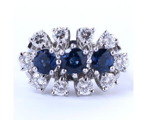 18 kt. Witgouden cocktailring. Centraal bezet met drie blauwe saffieren met een totaalgewicht van ca. 1.20 ct. In een entoura