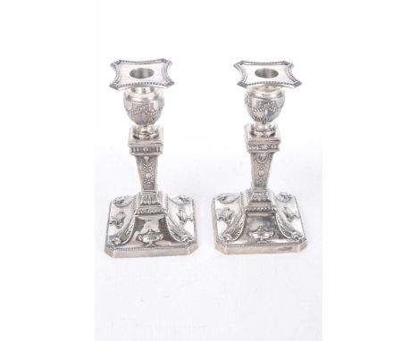 An Edwardian pair of silver candlesticksOf knopped form, the capitals with ribbon and swag decoration, with urn and ram head 