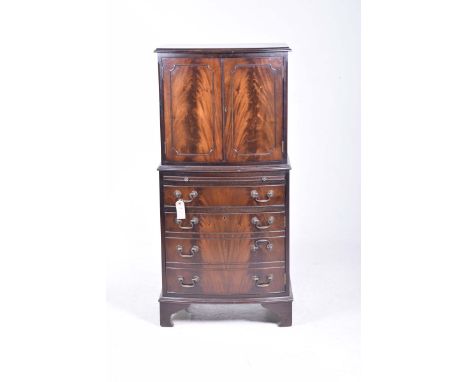 A mahogany drinks cabinet in the form of a Georgian linen press,The bowfront cabinet with two cabinet doors above a sliding t
