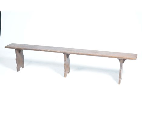 A rustic oak bench,The rectangular top with rounded corners supported on three shaped bracket supports, 203x 41x 23cm.