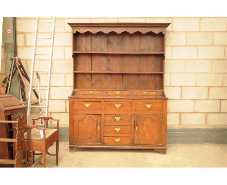 An 18th Century Welsh oak high back dresserWith a moulded cornice and a scalloped frieze above two enclosed shelves and a low
