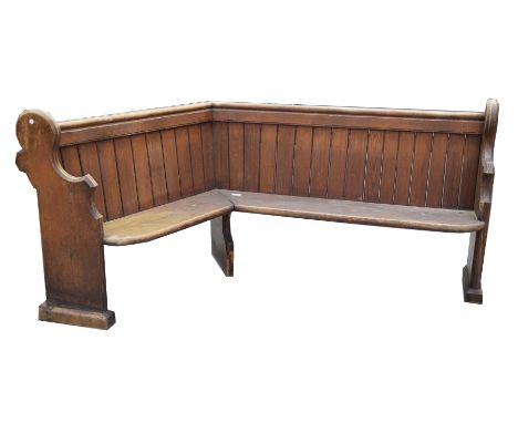A late 19th early 20th Century pitch pine church pewOf angled form with a rear book trough, raised on shaped bracket supports