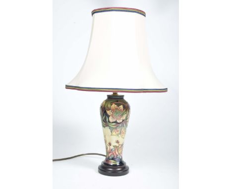 A Moorcroft table lamp, 20th CenturyDecorated with flowers, height of table lamp 30cm, complete with a cream lamp shade. (sol