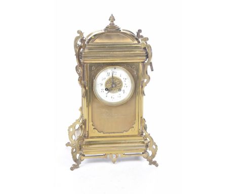 An early 20th Century brass cased mantle clockWith an urn shaped finial above a caddy top, and a white enamel dial, Arabic  n