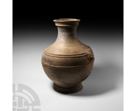 Han Dynasty, 206 B.C.-220 A.D. A grey ceramic jar or hu vessel with waisted and collared neck, splayed and collared foot and 