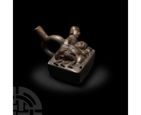 2nd-5th century A.D. A ceramic stirrup bottle with cuboidal body featuring a figural scene composed of a man and woman reclin