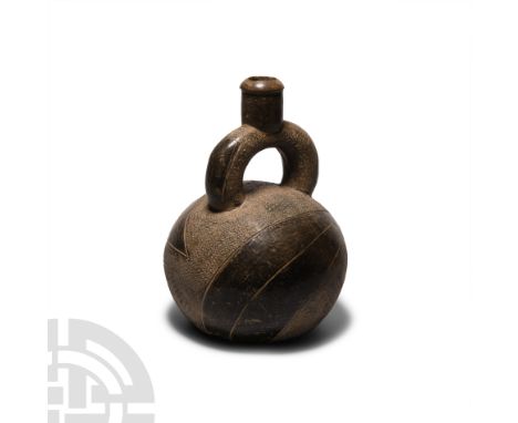 10th-3rd century B.C. An elegant and early black ware stirrup vessel with bulbous body, decorated with triangular forms and p
