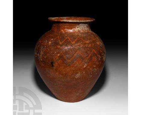 2nd millennium B.C. A large glazed terracotta storage vessel with piriform body, waisted neck and everted rim, painted with c