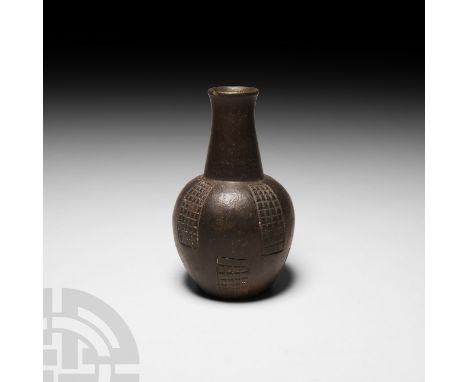 15th century A.D. or earlier. A black ware bottle with piriform body and waisted cylindrical neck, incised rectangular panels