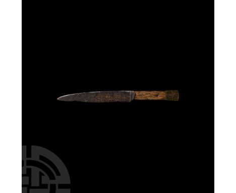 Circa 15th-16th century A.D. A scale-tanged iron knife with one cutting edge and wood scales, sub-rectangular brass pommel wi