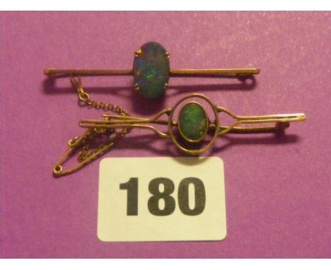 A gold bar brooch set with a dark opal, plus another set with a blue green opal.