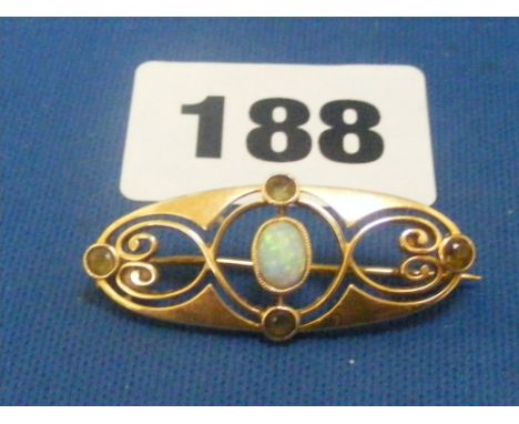 A 15ct gold brooch set with central opal with open scroll work and four small peridot.
