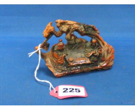 An unusual finely carved ornament of two Chinese gentlemen seated playing a game with trees in the background. 