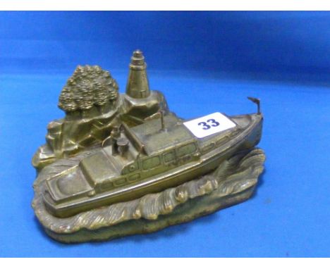 A vintage metal ornament of a boat at sea with lighthouse in the background. Marked JB 278 and with a small stud to the rever