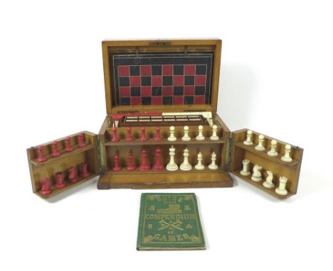 An Edwardian oak cased games compendium with hinged lid, folding front and two lift-out trays, enclosing tooled leather board