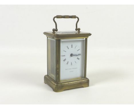 A modern brass cased carriage clock by Norman & Sons, 8 by 6.5 by 11cm high, in original plastic presentation case.