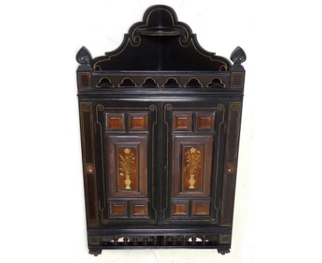 An Edwardian ebonised corner cabinet, decorated to the twin doors with gilt vases of flowers, turned spindles and pierced gal