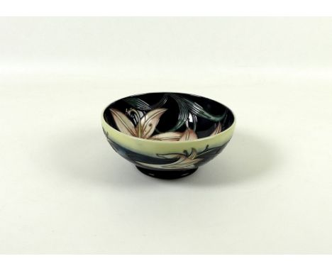 A Moorcroft bowl, designed by Philip Gibson, decorated with pink lilies on navy blue ground, base marked with blue Moorcroft 