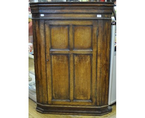 An oak hanging corner cupboard, with a four panel door, 80 cm wide