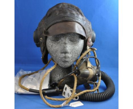 An RAF pattern suede lined leather flying helmet, with Bakelite ear pieces stamped AM, an oxygen mask with tube and clip, and