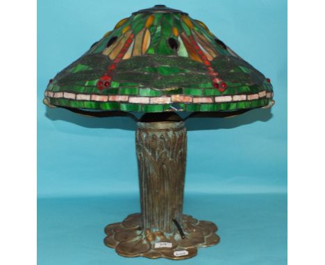 A stylised table lamp, the bronzed base in the form of lilies, the glass shade decorated dragonflies, 53 cm high