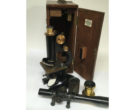 A Beck Ltd microscope in a fitted mahogany case with two lenses and Military gun sight.