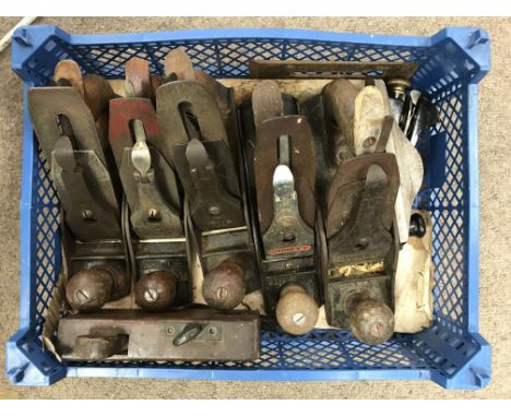 A wooden box an a blue plastic crate of woodworking tools including a large collection of planes.