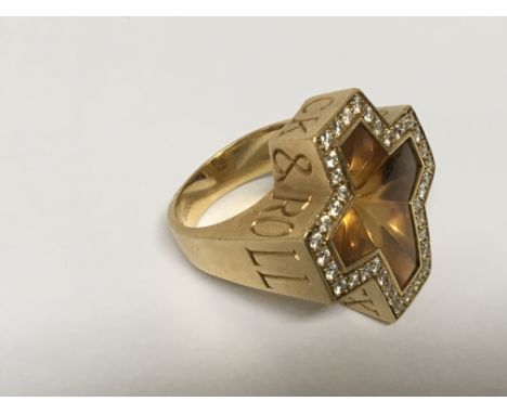 A large 18carat Gold ring set with diamonds, and an amber citrine. The ring with the inscription Sex Drugs and Rock and Roll.