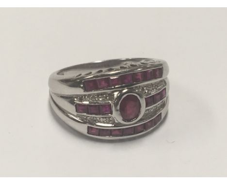 An 18carat white gold ring set with one central ruby with three rows of Ruby’s.ring size O-P.