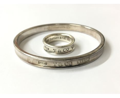 A solid silver Tiffany & Co bangle, with conforming Tiffany ring, approx ring size R. The exterior of each is marked for Tiff