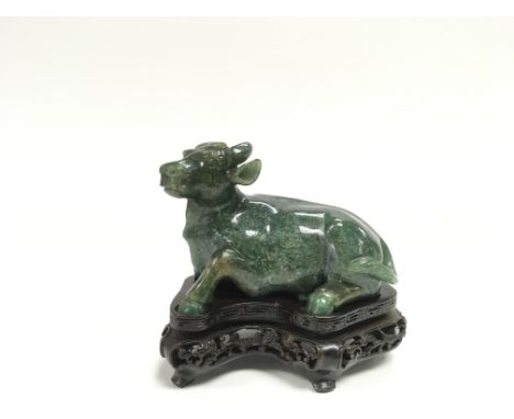 A 20th century green jade carving of a cow with a carved wooden base