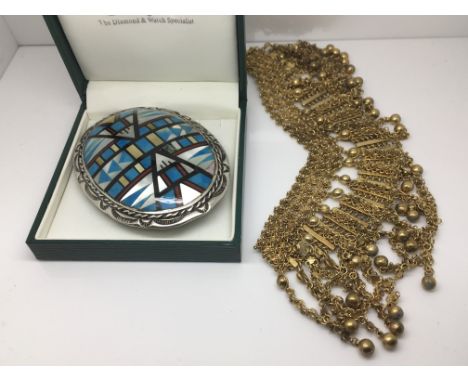An American sterling silver and enamel buckle with geometric designs and a gilt metal necklace (2).