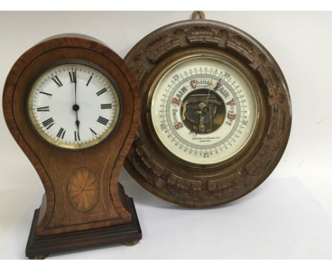 An Edwardian inlaid Mahogany mantel clock with a white enamel dial and a barometer with visible mechanism. in a carved walnut