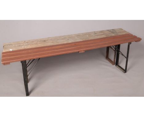 A pair of vintage slatted trestle benches, with folding cast metal supports. (181cm length x 26cm width, 52cm height)  