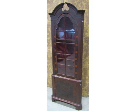 A Georgian style oyster veneered two sectional free standing corner cabinet, with broken arch pediment over a glazed panelled