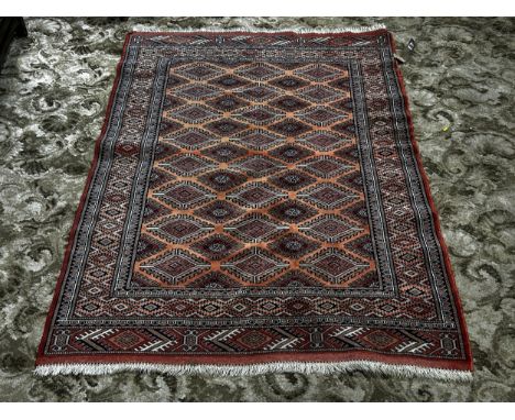 A Turkoman carpet with a central panel of geometric diamond medallions on a peach ground,  157cm x 115cm approx 