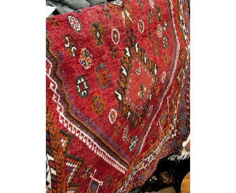 A Turkoman type carpet with a linked diamond medallions on a red ground, 240 x 160cm approx
