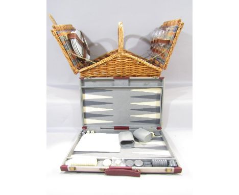 A cane picnic basket with twin flaps opening to reveal, four plates, four wine glasses, with a  zippered insulated food pouch