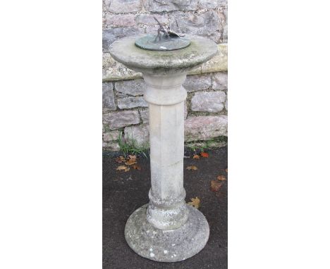 A weathered three sectional cast composition stone sundial  with octagonal pillar supporting a circular top and dial with pie