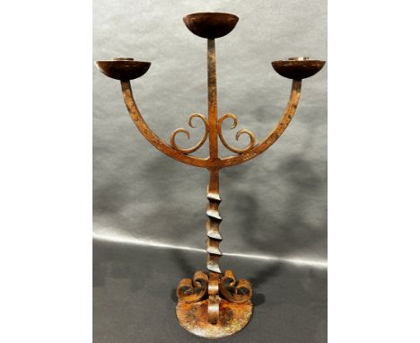 A cast iron three branch candlestick with a square twisted column raised on four scrolls and disc base, 54.5cm high. 