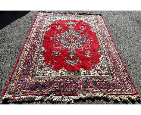 A large Turkish carpet with an extended central panel on a red ground and running floral borders,300 x 200cm approx 