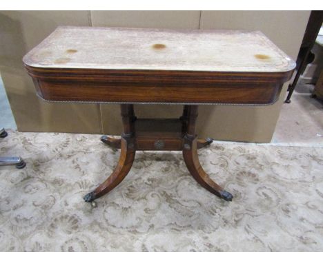 A Regency rosewood foldover top card table, raised on a quadruped platform, with sabre supports and lions paw feet and furthe
