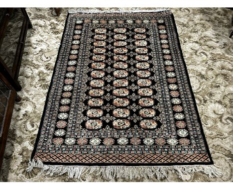 A Bokhara type carpet with three  rows of twelve small elephant foot gul on a black ground, 167cm x 120cm approx and another 