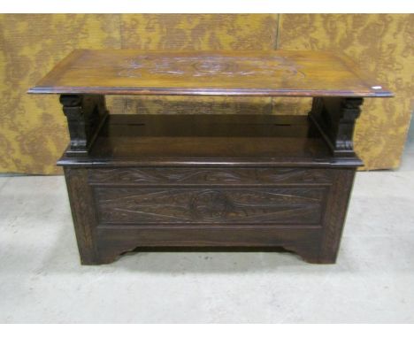 A carved oak monks bench with rising and falling lid over box base with carved detail 